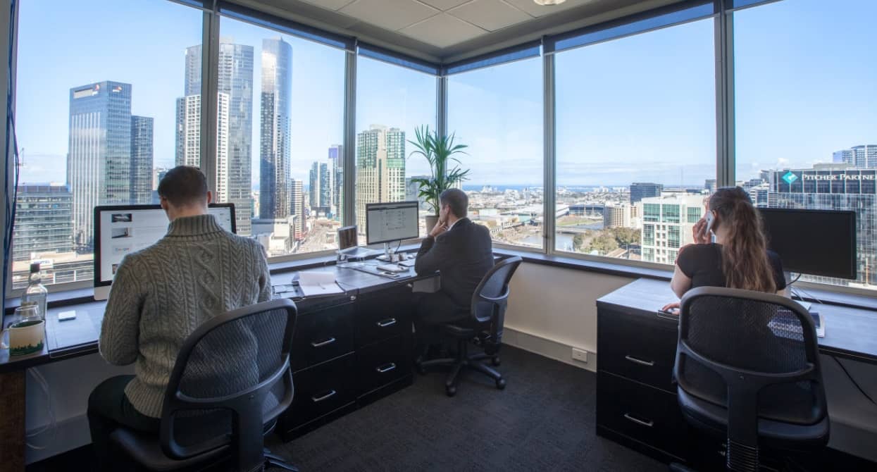 Three employees working from a serviced office with views of Melbourne CBD
