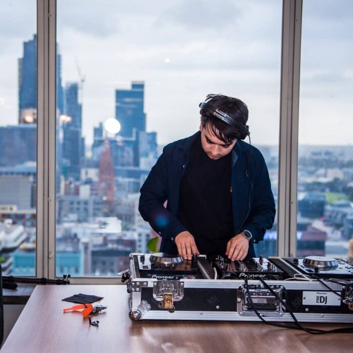 A DJ djing in front of the view of Melbourne's CBD